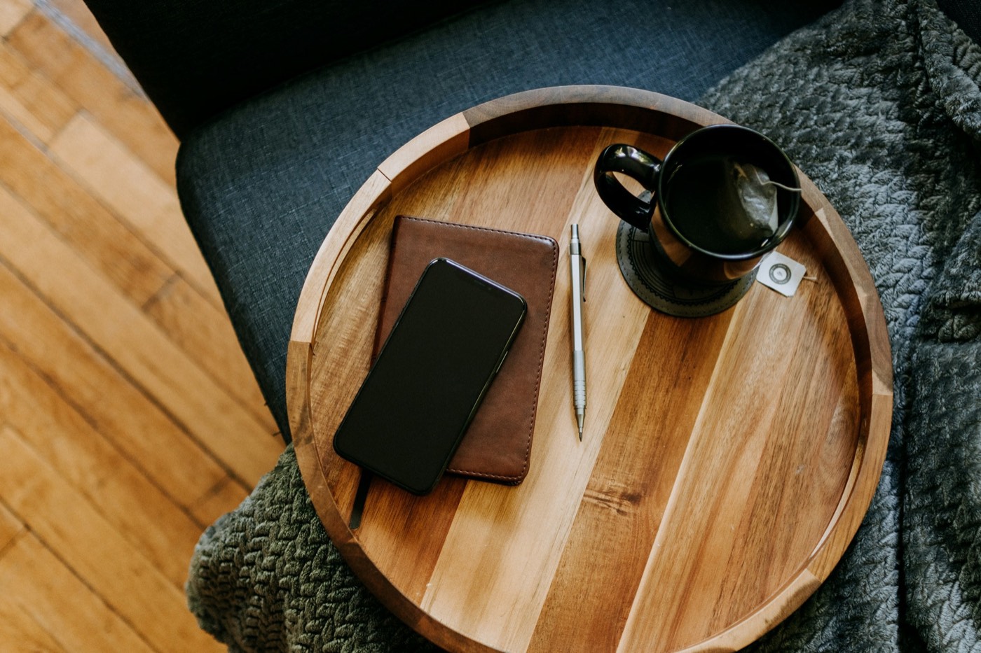 A notebook, a pen and a cup of coffee on a round wooden tray