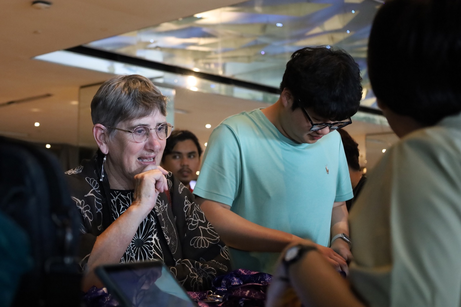 Volunteers at a registration table helping arriving guests, lanyards and name badges spread out in front of them