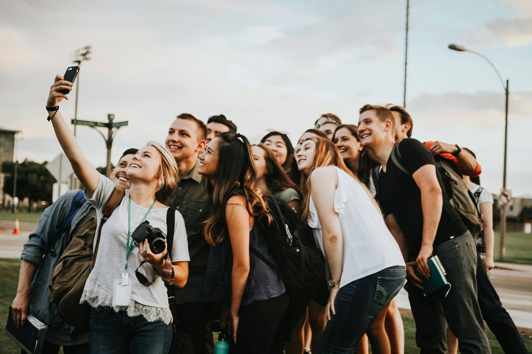 A group of college students with lanyards crowding together for a selfie outdoors