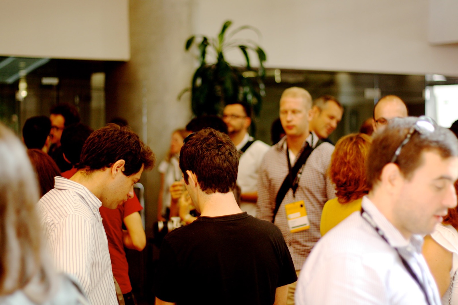 A crowded conference coffee break, people with lanyards talking in small groups