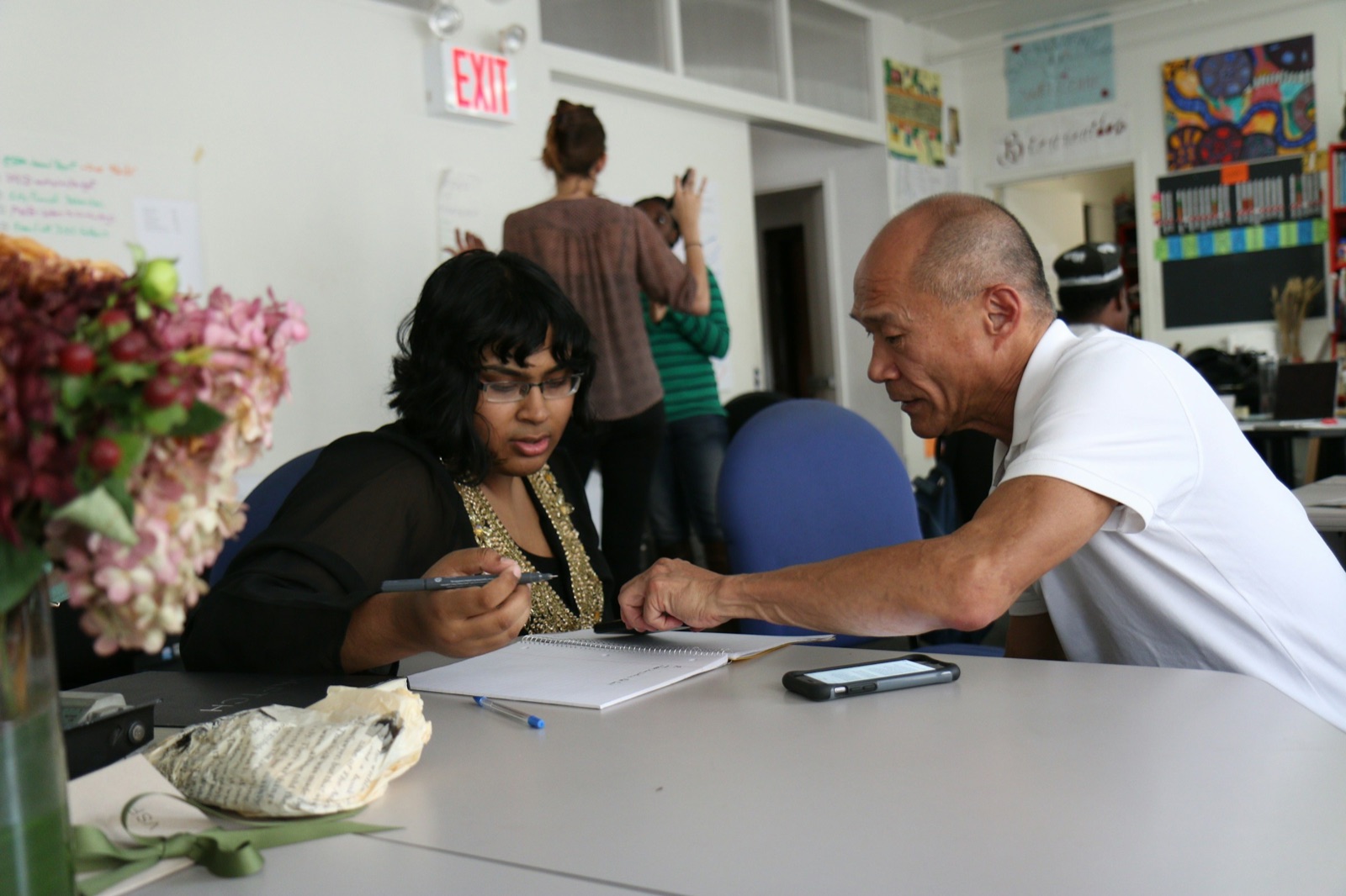 An older man and a younger woman working through notes together at a table